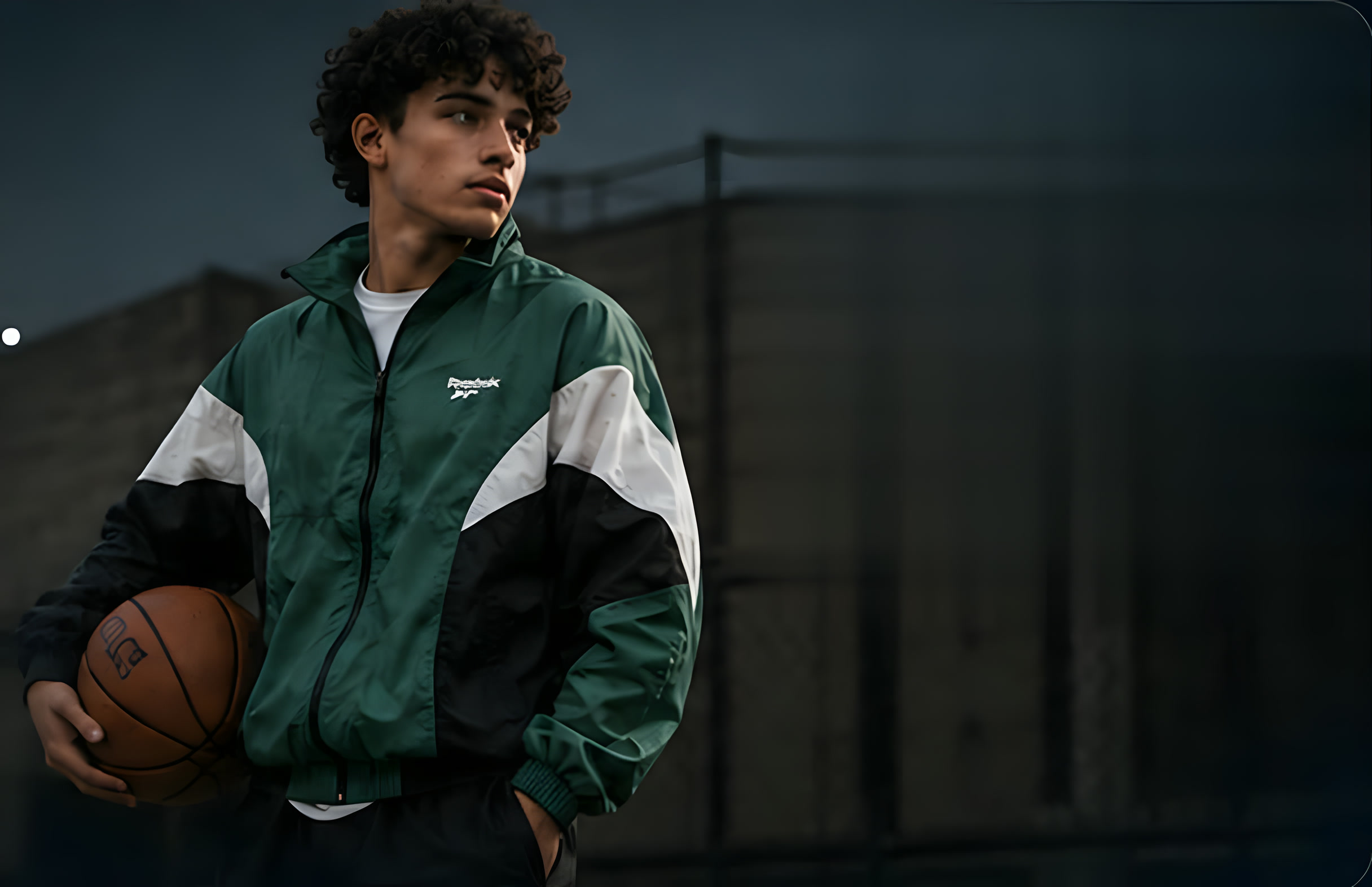 Athlete holding a basketball wearing a green vintage windbreaker