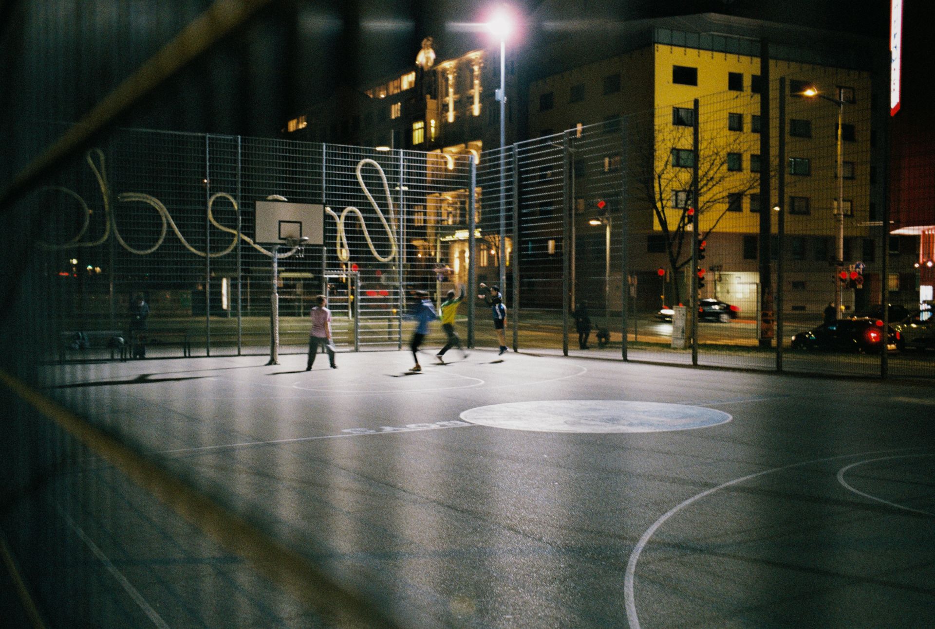 Empty basketball court at dusk under streetlights